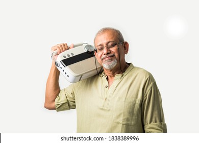 Indian asian old man or male senior adult listening to music on vintage radio using headphones and dancing, isolated against white background