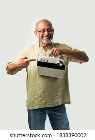 Indian Asian Old Man Or Male Senior Adult Listening To Music On Vintage Radio Using Headphones And Dancing, Isolated Against White Background