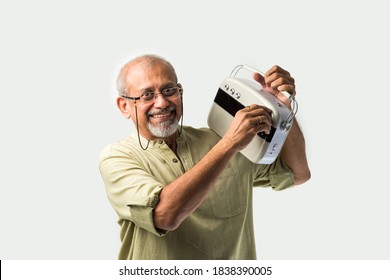 Indian Asian Old Man Or Male Senior Adult Listening To Music On Vintage Radio Using Headphones And Dancing, Isolated Against White Background