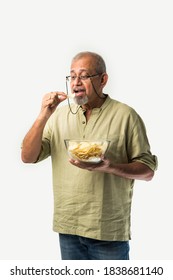 Indian Asian Old Or Retired Senior Man Eating Potato Chips On White Background