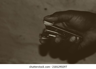 An Indian Or Asian Rich Man Known As Jamindaar Holding A Stapler For Staples On The Paper. Hand Visible. Blurred Background.