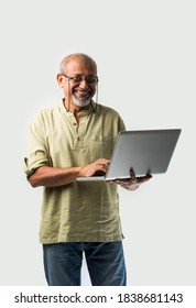 Indian Asian Senior Adult Man Or Grandpa Using Laptop And Holding Paper Currency Notes Against White Background