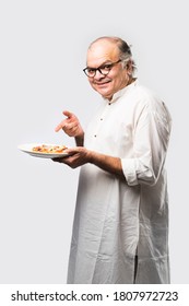 Indian Asian Senior Or Old Man Eating Pizza While Standing Isolated Against White Background