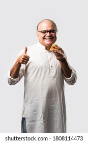 Indian Asian Senior Or Old Man Eating Pizza While Standing Isolated Against White Background