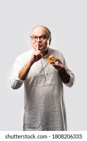 Indian Asian Senior Or Old Man Eating Pizza While Standing Isolated Against White Background