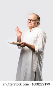 Indian Asian Senior Or Old Man Eating Pizza While Standing Isolated Against White Background