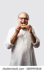 Indian Asian Senior Or Old Man Eating Pizza While Standing Isolated Against White Background