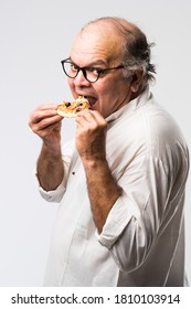 Indian Asian Senior Or Old Man Eating Pizza While Standing Isolated Against White Background