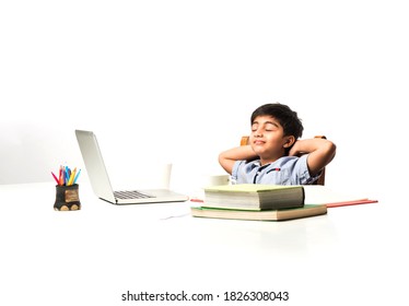 Indian asian small kid tired with studies hence stretching or taking nap at study table at home