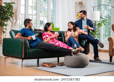 Indian asian two couples meeting at home on a coffee and having communication while sitting on sofa - Powered by Shutterstock