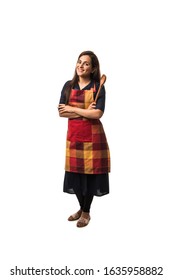 Indian / asian woman chef wearing Apron and holding wooden spatula while standing isolated over white background