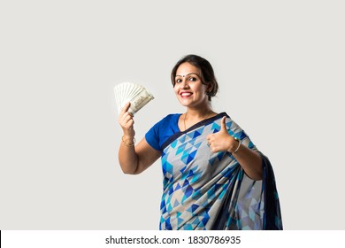 Indian asian woman in sari or saree showing or holding paper currency notes or money fan against white background