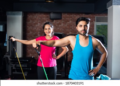 Indian asian young couple exercising with resistance band in the gym - Powered by Shutterstock