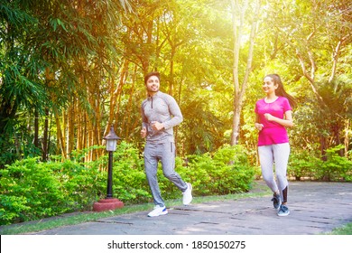 Indian Asian Young Couple Jogging, Running, Exercising Or Stretching Outdoors In Park Or Nature