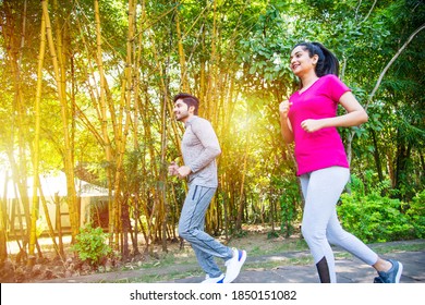 Indian Asian Young Couple Jogging, Running, Exercising Or Stretching Outdoors In Park Or Nature