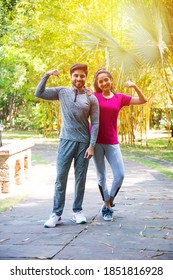 Indian Asian Young Couple Jogging, Running, Exercising Or Stretching Outdoors In Park Or Nature