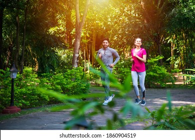 Indian Asian Young Couple Jogging, Running, Exercising Or Stretching Outdoors In Park Or Nature