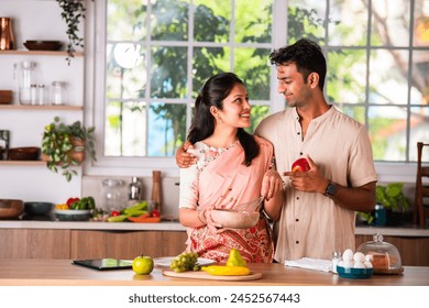 Indian asian young couple working in kitchen preparing meal - Powered by Shutterstock