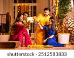 Indian Asian young couples or friends lighting diya or samai on Diwali, celebrating the Festival of Lights together with vibrant cultural traditions