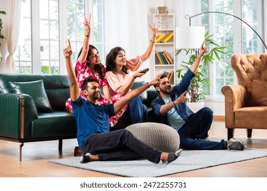 Indian asian young friends couples watching television while siting together at home on sofa - Powered by Shutterstock