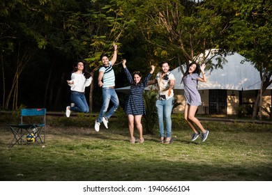 Indian Asian Young Friends Dancing Or Jumping While Camping Near Tent, Outdoors In Jungle