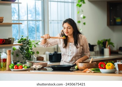 Indian asian young woman enjoy cooking healthy meal in modern kitchen - Powered by Shutterstock