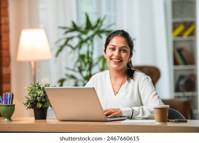 Indian asian young working professional female working on laptop at home wears smart formals - Powered by Shutterstock