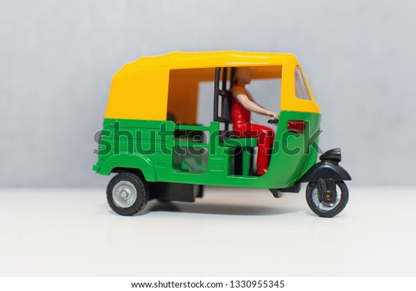 An Indian auto rickshaw on white background. A\
yellow green tuk-tuk with a driver. Colorful model Tricycle taxi. A\
rickshaw toy.\
