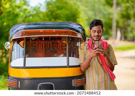 Indian auto rickshaw three-wheeler tuk-tuk taxi driver man using smartphone.