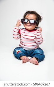 Indian Baby Boy Or Infant Trying To Wear Dark Glasses Or Sunglasses Or Goggle, Isolated Over White Background