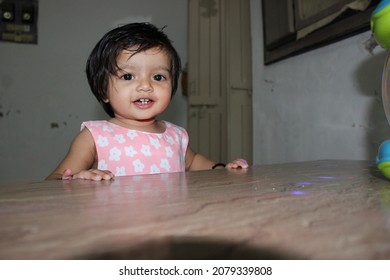 Indian Baby Girl Standing Near Table Top By Holding With Two Hands With Smiling Face Expressing Joy Of First Steps Of Walking On Herself