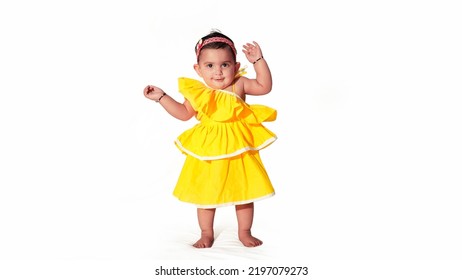 Indian Baby Girl Standing Pose Wearing Light Yellow Frilled Frock, Isolated On White Background