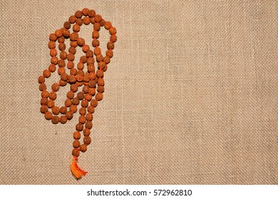 Indian Beads Of Rudraksha Are On The Background Burlap.