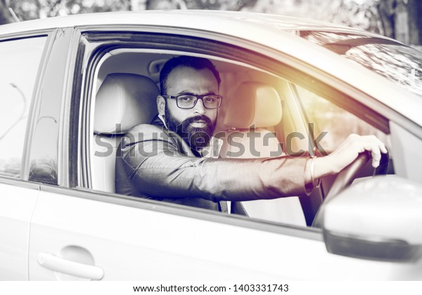 Indian\
Bearded businessman driving car, selective\
focus