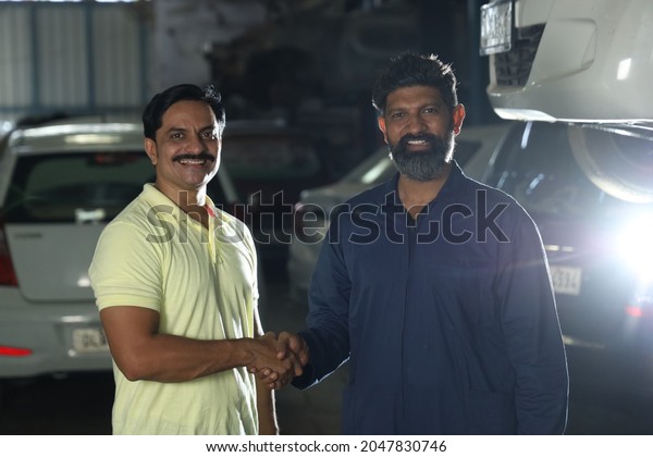 Indian bearded car mechanic standing with the
happy customer shaking hands together. Portraying customer
satisfaction to the whole scene the customer is joyous after
getting their car
repaired.