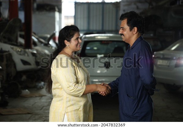 Indian bearded car mechanic standing with the\
happy customer shaking hands together. Portraying customer\
satisfaction to the whole scene the customer is joyous after\
getting their car\
repaired.