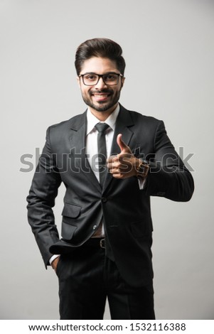 Indian Bearded Male businessman celebrating success with thumbs up or raising fist while standing isolated over white background