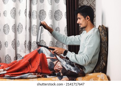 Indian Bearded Young Man Opening Laptop For Start Office Work Or Video Call Getting Ready For Work In The Morning At The Bed Near Window In A Beautiful House Starting Of A Work Day