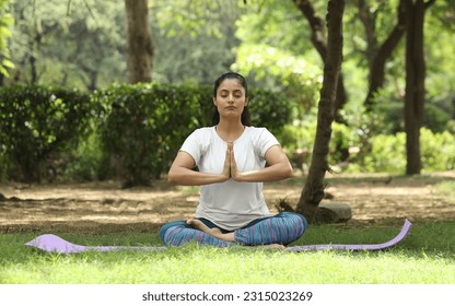 Indian Beautiful woman doing breathing yoga exercise in the summer park, Asian female meditation pose, healthcare. copy space - Powered by Shutterstock