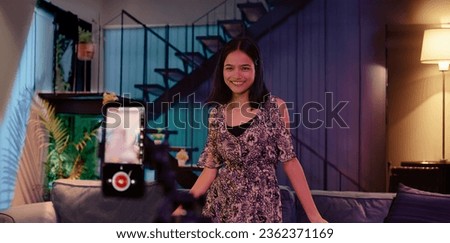 Indian beautiful young smiling bloggers shooting recording dance moves on smartphone camera in living room. Female dancer making popular trendy music content video for social media account stories