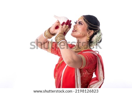 Indian Bengali woman is blowing a conch shell. Individually portrait on a white background.