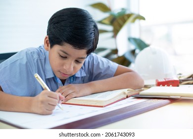 Indian Boy Doing His Homework, Little Boy Learns With His Books In Study Room