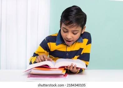 Indian Boy Reading Book Over Study Table At Home