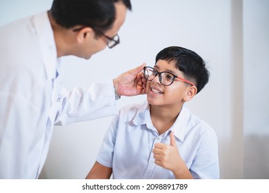 Indian boy try eyeglass frames and thumb up  it's perfect for him, optometrist or optometrist  helps to get new glasses for boy - Powered by Shutterstock