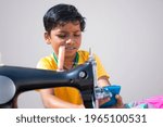 Indian boy using mobile with sewing machine in rural India
