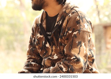 An Indian boy wearing brown camouflaged jacket and jeans while sitting on the marble bench, depressed - Powered by Shutterstock