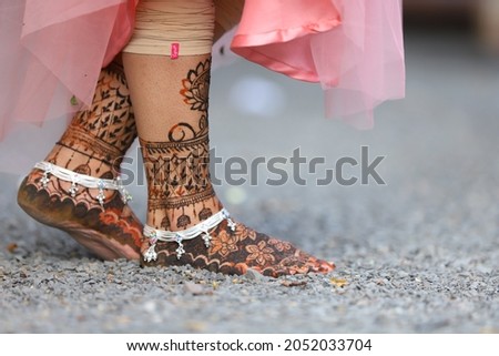 Indian bridal wearing silver Payal anklets and showing foot mehndi design. Indian wedding 