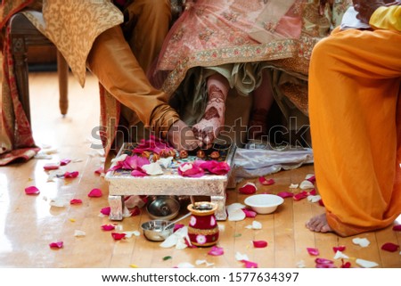 Indian bride and groom stepping on decorated nuts