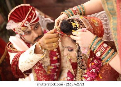 Indian bride and groom wearing traditional dress, Indian Bride and groom posing on their wedding, Indian groom dressed in white Sherwani and red hat with stunning bride in dark red lehenga - Powered by Shutterstock