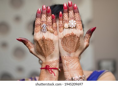 Indian Bride Hiding Her Face With Hands By Showing Mehendi Tattoo And Wearing Rings And Bracelet